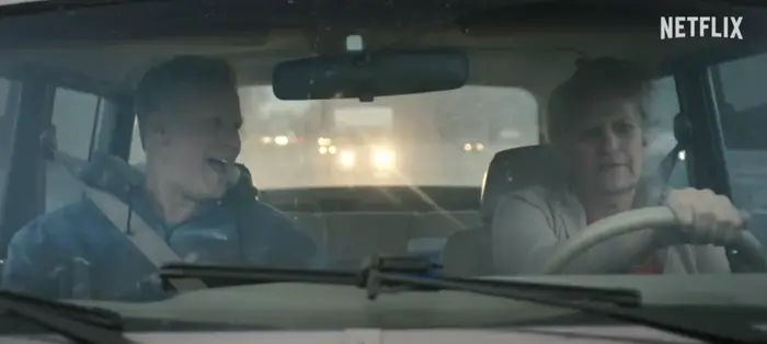 Bruce McCulloch and Scott Thompson driving a car, smiling, in a scene from a Netflix show